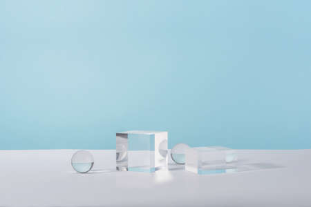 Pedestal cosmetic display glass podium platform with stylish props for product presentation, cosmetics geometric stand, mockup scene for jewellery mock up. Acrylic blocks and balls on blue backgroundの写真素材