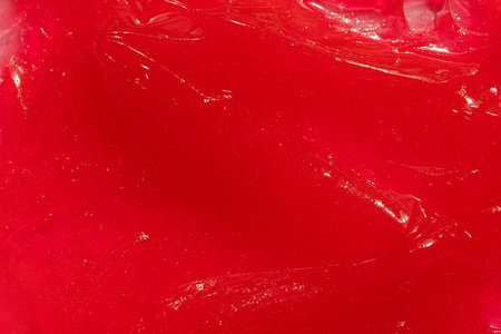 Red gel texture. Cosmetic clear liquid cream smudge. Skin care product sample closeup. Toothpaste or...