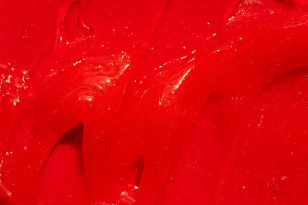 Red gel texture. Cosmetic clear liquid cream smudge. Skin care product sample closeup. Toothpaste or wax backgroundの写真素材