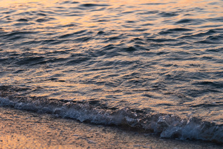 Sea wave splashes close up. Ripple sea ocean water surface with golden sunset light.の写真素材