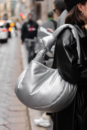 Milan, Italy - September, 21, 2022: Stylish women wearing black leather cape and silver shiny handbag, street style outfit detailsのeditorial素材