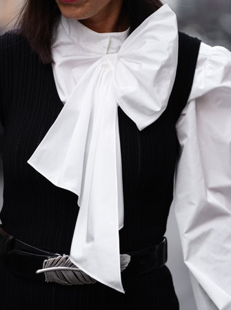 Milan, Italy - September, 21, 2022: woman wearing white blouse with blow, puffy long sleeves, black belt and black gilet, street style outfit detailsのeditorial素材