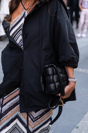Milan, Italy - September, 23, 2022: woman wears black short sleeves shirt, black leather puffy cassette handbag from Bottega Veneta, glitter striped knitted dress from Missoni, street style detailsのeditorial素材