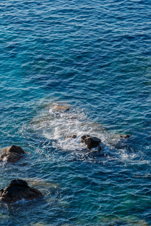 Waves on rocky beach, sea shore with waves crushing over the big rocks, summer sunny dayの写真素材