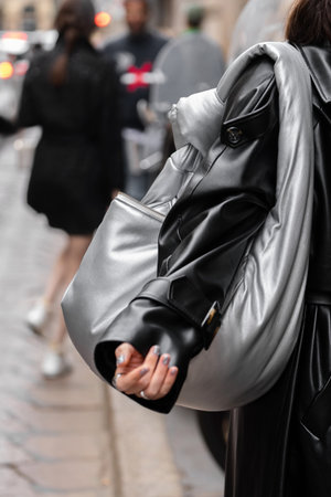 Milan, Italy - September, 21, 2022: Stylish women wearing black leather cape and silver shiny handbag, street style outfit detailsのeditorial素材