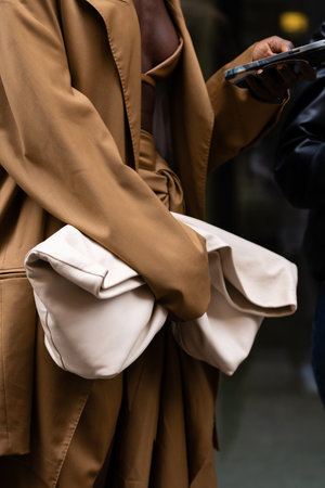 Milan, Italy - September, 21, 2022: Stylish women wearing camel brown coat, matching skirt and crop top, brown high heels leather boots, holding beige leather handbag, street style outfit detailsのeditorial素材