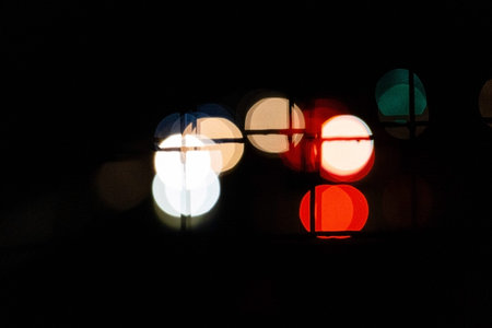 Night bokeh lights on the rod, abstract blur defocused background through the grid
