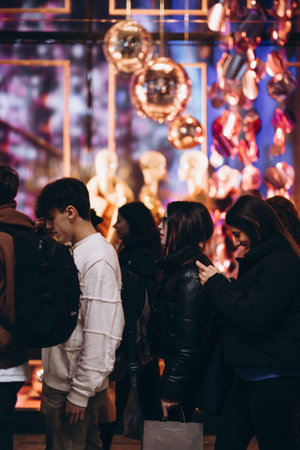 Milan, Italy - November, 11, 2023: young smiling people passing by front of the fashion store shop decorated to christmasのeditorial素材