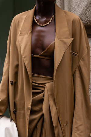 Milan, Italy - September, 21, 2022: Stylish women wearing camel brown coat, matching skirt and crop top, brown high heels leather boots, holding beige leather handbag, street style outfit detailsのeditorial素材