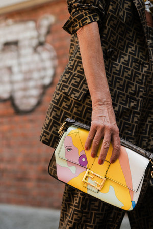 Milan, Italy - June, 18, 2022: woman wears medium Baguette bag with fashion illustration on it, street style accessories.のeditorial素材