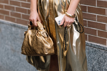 Milan, Italy - September 20, 2023: fashioner wearing Bottega Veneta metallic gold shoulder bag. Fashion blogger outfit details, street styleのeditorial素材