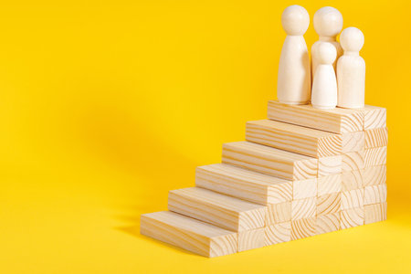 Businessman climbing stairs. Business growth success process, career ladder. Ambitions concept. Wooden figurine on yellow backgroundの写真素材