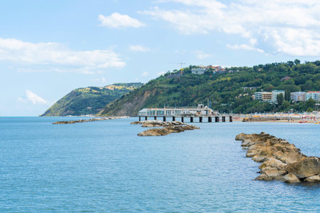 Coastal landscape on bright day with partly cloudy skies. Rocky formations protruding from the calm blue waters of the oceanの写真素材