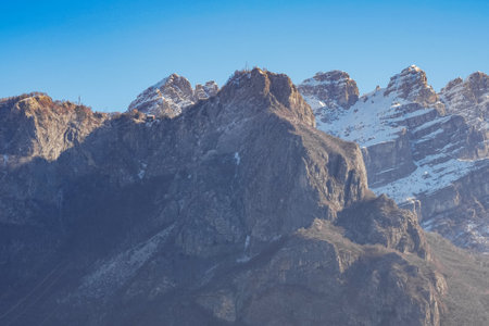 Mountain covered with snow and fog. Alpine landscape in Italy, Europe. Snow-capped mountains against blue skyの写真素材