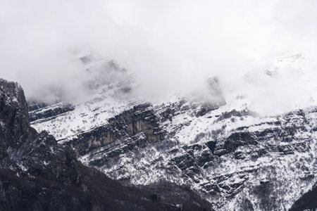 Mountain covered with snow and fog. Alpine landscape in Italy, Europe. Snow-capped mountains against blue skyの写真素材