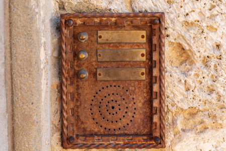 close up of an old rusty intercom embedded in weathered stone wall, blending technology with traditional architectureの写真素材