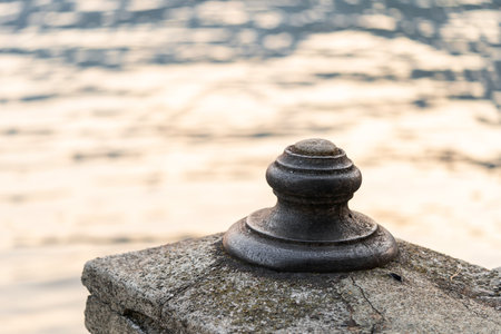 close-up of weathered stone post with water in background at sunsetの写真素材