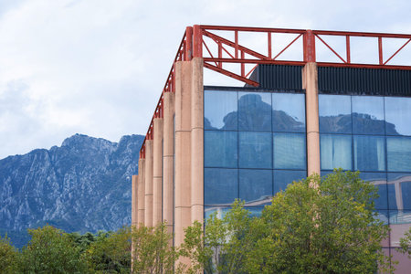 A modern building with reflective glass windows showcasing a mountainous backdrop.