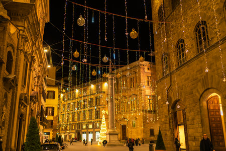 Florence, Italy - August, 31, 2022: historical building illuminated with sparkling lights and festive decorations, casting a warm glow on a lively evening street sceneのeditorial素材
