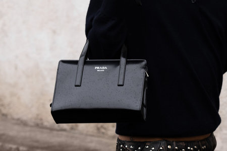 Milan, Italy - February, 22, 2024: woman wears Prada bag, fashion blogger outfit details, street...