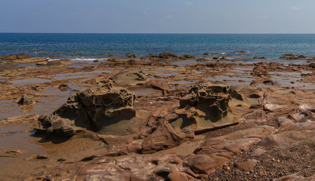 Close-up of eroded rocks forming intricate tide pools along a Mediterranean coastline, with the...