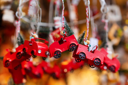 Red metal toy cars adorned with small green Christmas trees are hanging as festive ornaments. These decorations capture nostalgic holiday feel, perfect for adding charm to Christmas treeの写真素材
