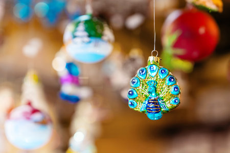 Vibrant peacock ornament is displayed hanging at festive market, surrounded by other decorative holiday ornaments. Detailed craftsmanship adds charm to the holiday spiritの写真素材