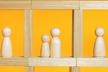 Wooden figurines on yellow backgroundの写真素材