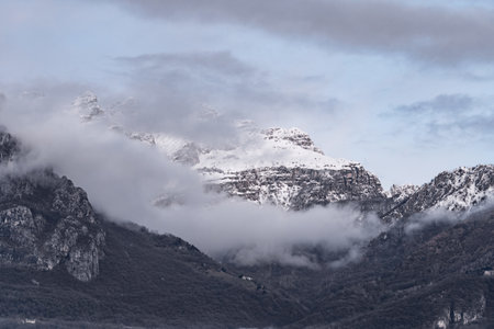Mountain covered with snow and fog. Alpine landscape in Italy, Europe. Snow-capped mountains against blue skyの写真素材