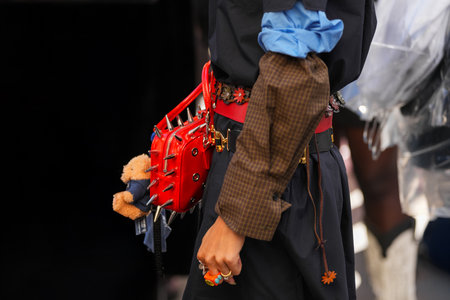 Paris, France - October, 4, 2025: Woman wears red Snapper Spike spiked shoulder bag Poppy Lissiman with plush toy accessory and colorful rings, street style lookのeditorial素材
