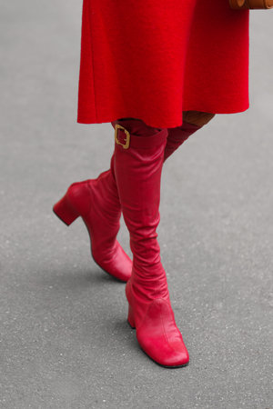 Paris, France - October, 6, 2025: Woman wears Miu Miu red knee high boots. Fashion outfit shoes detail, street style look accessory.のeditorial素材