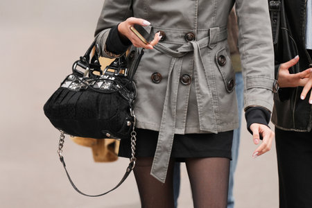 Paris, France - October, 6, 2025: Woman wears black Guess shoulder bag with metal details. Fashion outfit handbag detail, street style look accessoryのeditorial素材