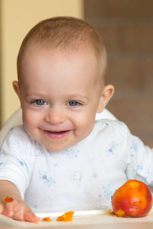 One year old baby eating a peachの写真素材