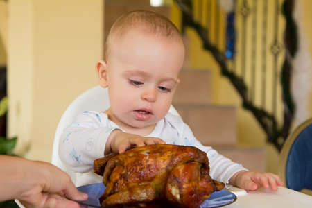 One year old baby boy eating a big grilled chickenの写真素材