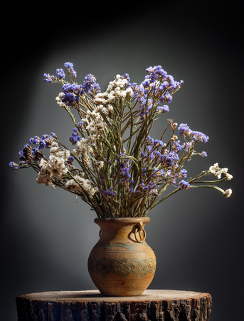 Bouquet of flowers in old vase on stumpの写真素材
