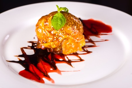 Cake with Scoop of ice cream with syrup and cherry on topの写真素材