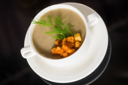 Tasty Cream soup with dry bread crumbs in white plate against black backgroundの写真素材