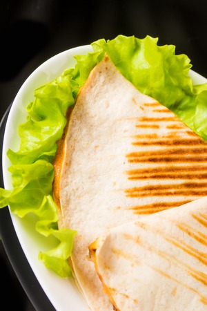 Healthy pita bread pizza on fresh green lettuce against black backgroundの写真素材