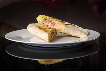 Two Fresh sandwiches with vegetables and meat on white plate isolated on black backgroundの写真素材
