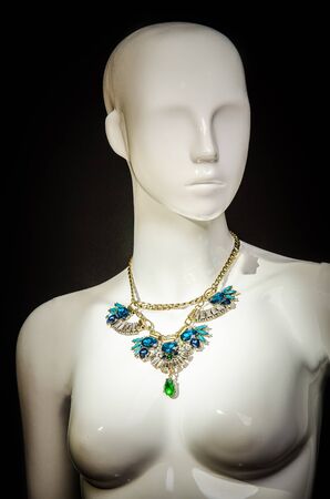 White mannequin with luxury necklace against black background.の写真素材