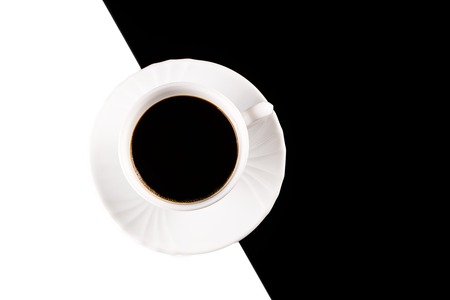 Top view of black coffee in white cup with plate on white and black backgroundの写真素材