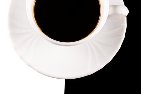 Top view of black coffee in white cup with plate on white and black backgroundの写真素材