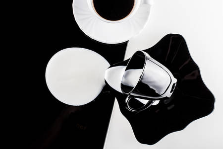 black and white coffee cups with plates on white and black backgroundの写真素材