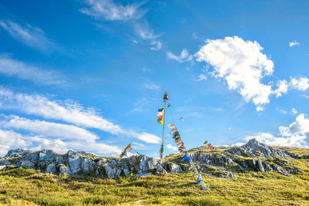 Construction with colorful flags against blue cloudy sky on the top of mountain