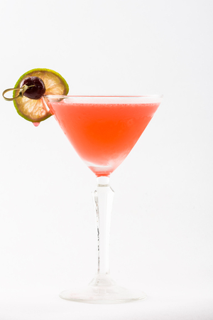 Orange cocktail beverage with lime and berry in martini glass on white backgroundの写真素材
