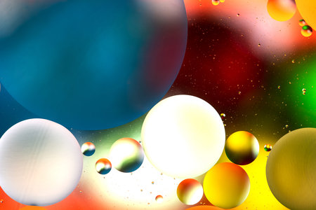 bright oily drops in water with colorful background, close-up