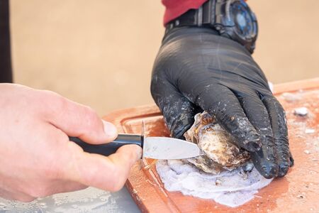 Man opening oyster on the market. Close up view.の写真素材