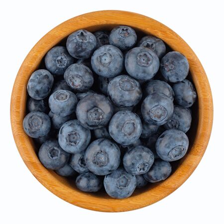 Ripe blueberries in wooden bowl isolated on white background. Top view.の写真素材