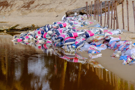 Thailand. Phuket - 08/05/18. Dirty brown water with garbage in canal.