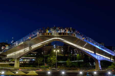 Moscow - 10 August 2018: Night view on soaring bridge with people in Zaryadye park.